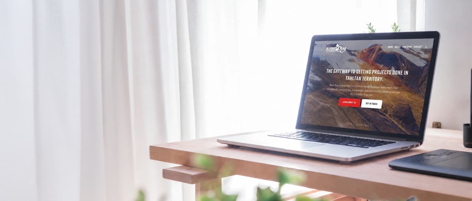 A sunlit desk with an open laptop showing a client website
