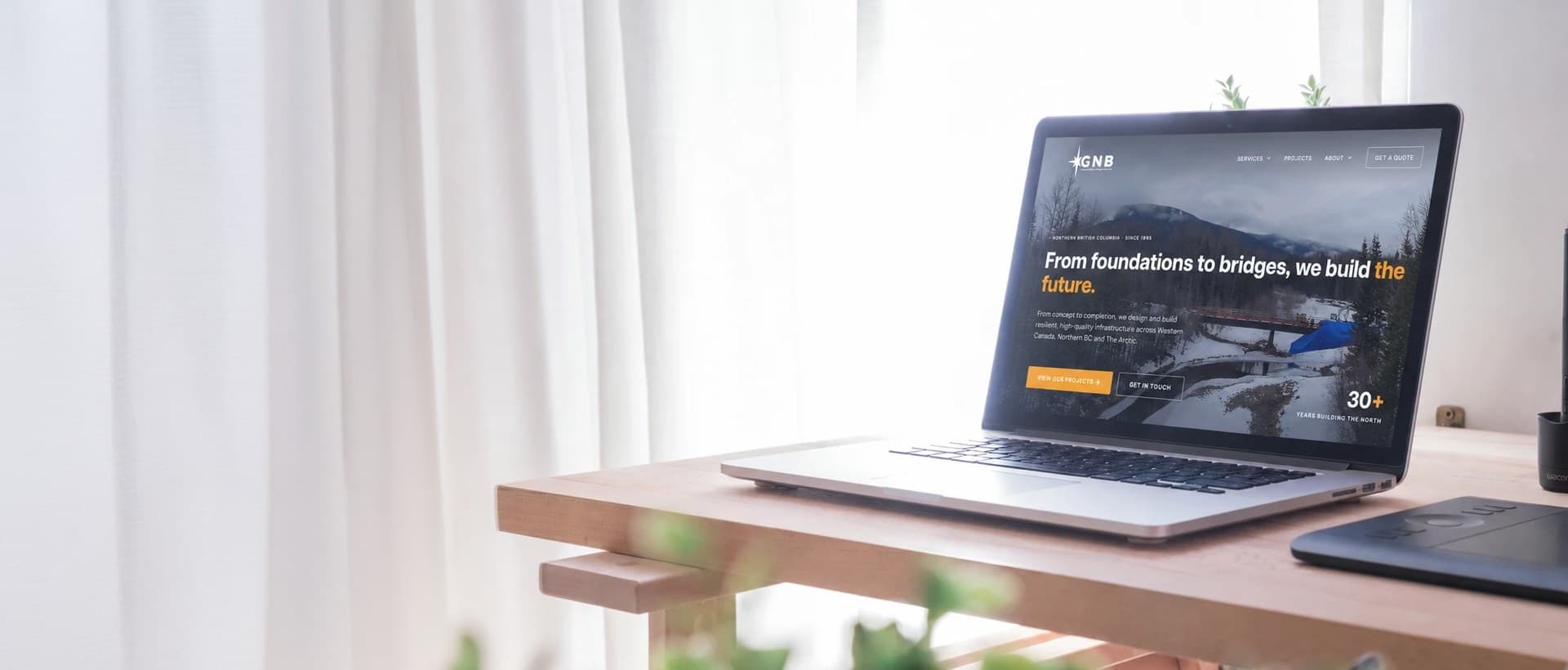 A sunlit desk with an open laptop showing a client website